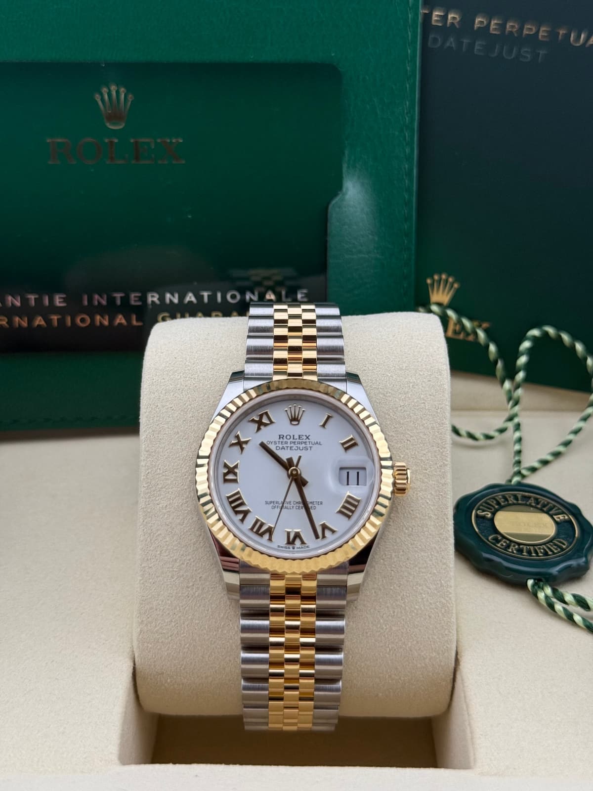 Rolex Datejust 31 Yellow Gold/Steel White Roman Jubilee 278273 - watch with gold and silver band on a display stand, with Rolex box in the background.
