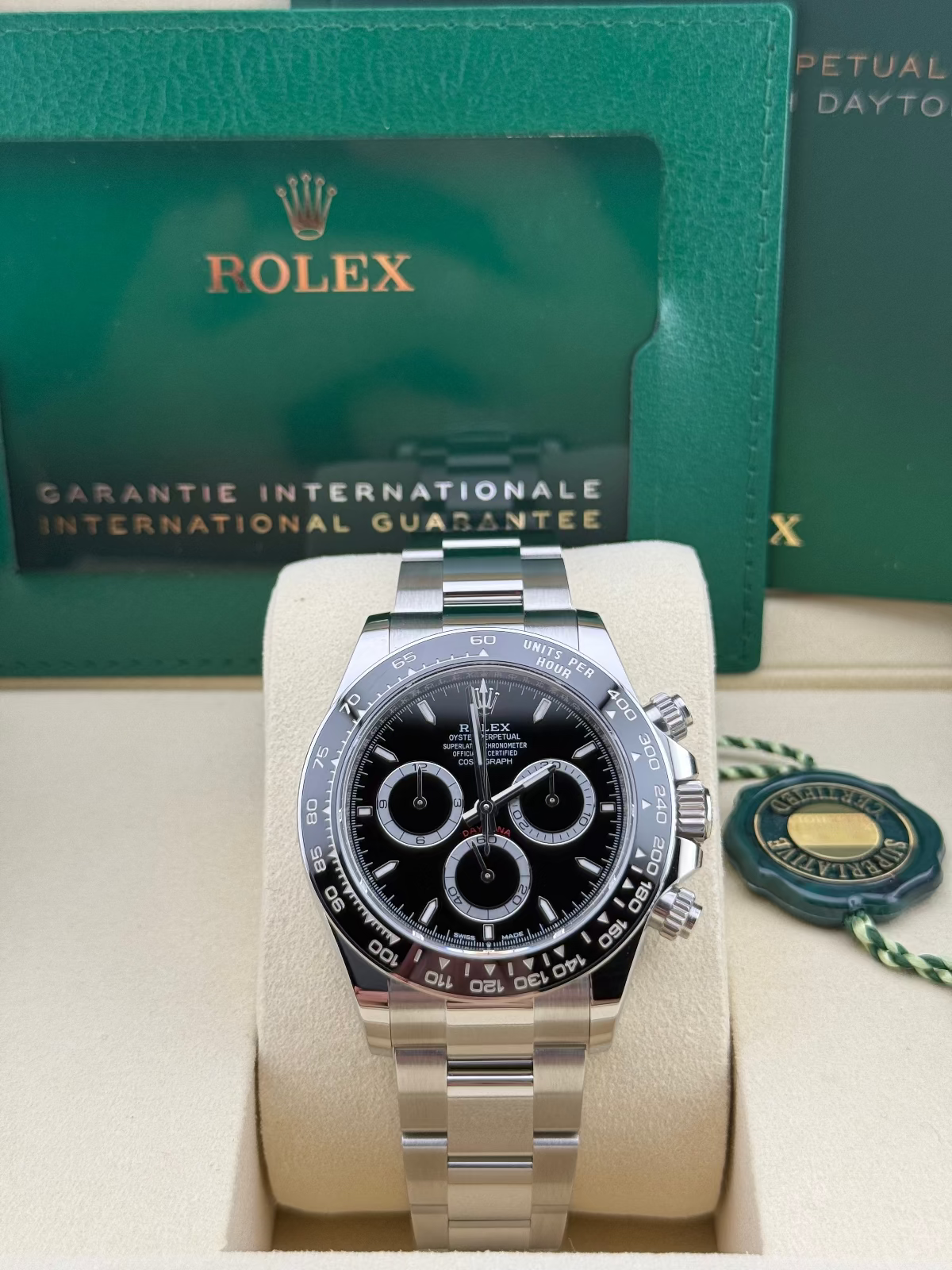 Rolex Daytona Stainless Steel Black Dial 126500LN – watch with green box and warranty card in the background